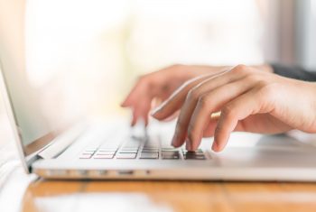 Closeup of business woman hand typing on laptop keyboard